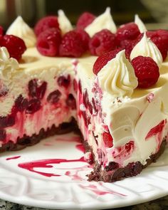 a white plate topped with a cheesecake covered in raspberries