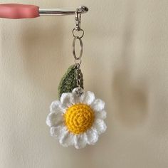 a crocheted flower keychain hanging from a hook on a white wall