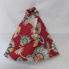 a red and blue flowered bag with a white bow on the top of it