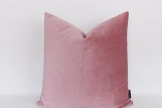 a pink velvet pillow sitting on top of a white wall