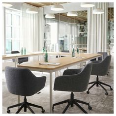 an empty conference room with chairs, tables and bottles on the table in front of large windows