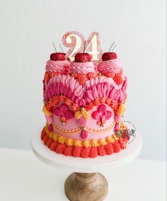 a pink and red cake with the number twenty nine on top is sitting on a pedestal