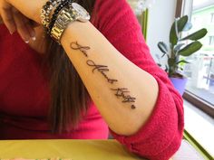 a woman sitting at a table with a tattoo on her arm that says, love