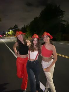 three women in red and white outfits standing on the side of a road at night