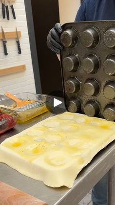 a person holding a muffin pan over a table