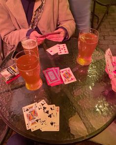 two people sitting at a table with cards and drinks