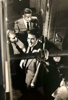 black and white photograph of two men in suits talking to each other on the subway