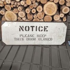 there is a sign that says notice please keep this door closed on the side of a pile of logs