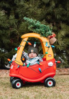 a baby in a toy car with a christmas tree on top