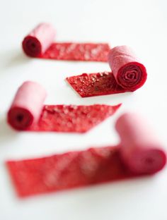 three rolled up pieces of candy sitting on top of a white table next to each other