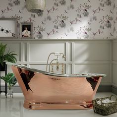 a bathroom with a large copper bathtub and wallpaper