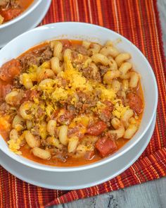 two bowls of chili macaroni soup on top of a red and orange place mat