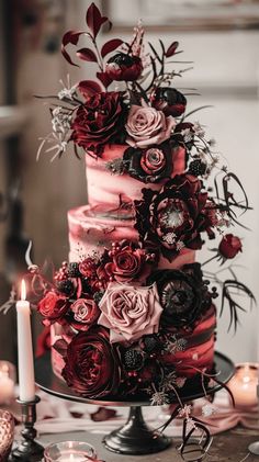 a wedding cake with red and pink flowers on the top is surrounded by other decorations