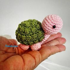 a small crocheted turtle sitting on top of someone's hand