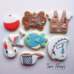 decorated cookies are arranged in the shape of boats, fish and fishing related items on a white surface