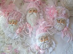 some pink and white christmas ornaments on a lace doily with flowers, pearls and santa's beards