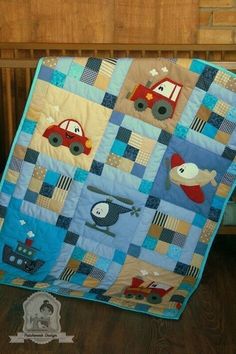 a baby quilt with cars and trucks on it in front of a crib bed