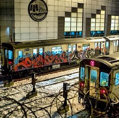 two trains covered in graffiti parked next to each other