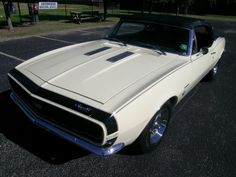 an old white muscle car parked in a parking lot