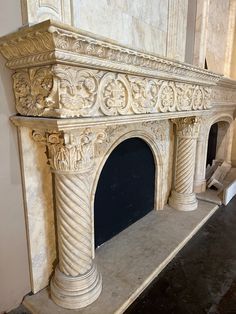 an old fireplace in the middle of a room with white walls and stone carvings on it