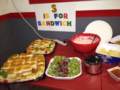 a table topped with lots of food next to a sign that says s is for sandwich