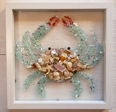 a crab made out of sea glass in a white frame