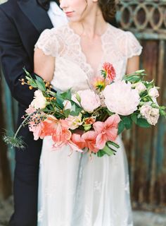 a bride and groom standing next to each other in front of a fence with flowers