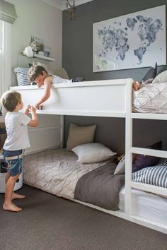 a little boy standing next to a woman on top of a bunk bed in a bedroom