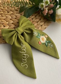 a green bow tie with the word peace written on it and flowers in the background