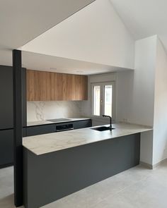 an empty kitchen with marble counter tops and wooden cabinets on the walls, along with black appliances