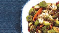 a white plate topped with broccoli, cauliflower and pomegranate