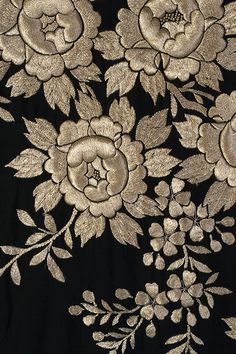 black and gold floral embroidered fabric with white flowers on the side, close up view