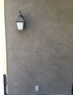 a light on the side of a building next to a wall with a door open