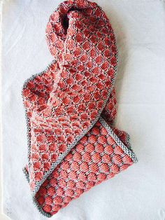 an orange and white knitted scarf laying on top of a tablecloth covered in paper