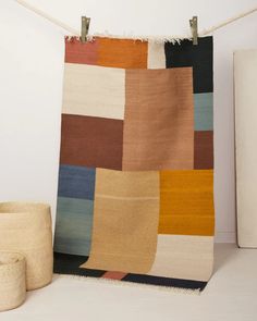 a multicolored rug hanging on a rope next to a vase and potted plant