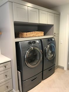 a washer and dryer in a laundry room with cabinets on the wall above them