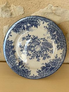 a blue and white plate sitting on top of a wooden table next to a stone wall