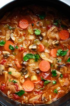 a stew with carrots, mushrooms and parsley in a crock pot on the stove