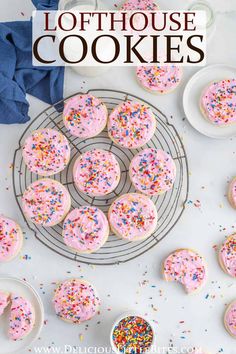 pink frosted sprinkle cookies on a cooling rack with blue napkins and white plates