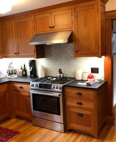 a kitchen with wooden cabinets and stainless steel stove top oven in the center of the room