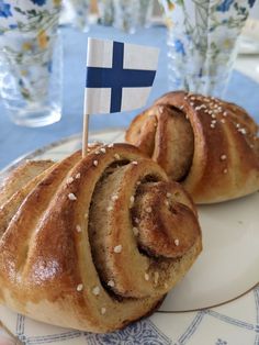 two bread rolls on a plate with a flag sticking out of the top one is blue and white