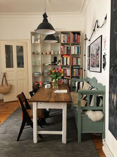 a dining room table with chairs and bookshelves in the background on a rug