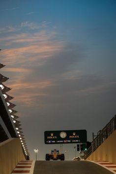 a race car is driving down the track at dusk with clouds in the sky behind it