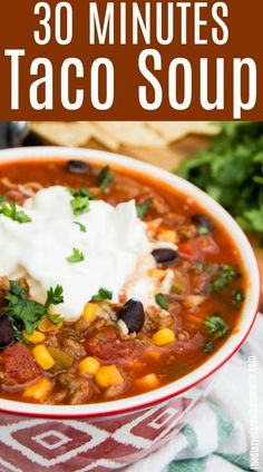 a bowl of taco soup with sour cream and cilantro in the background