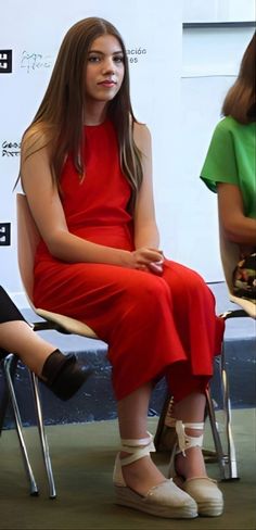 a woman in a red dress sitting on a chair