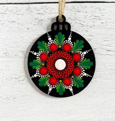 an ornament hanging from a string on a white wooden surface with red berries and leaves