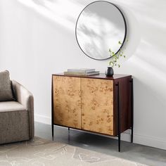 a living room with a chair, mirror and plant on the sideboard in front of it