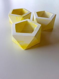 three small yellow vases sitting on top of a white table next to each other