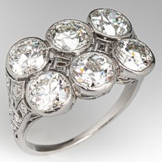 This spectacular circa 1910s ring features six (6) round old European cut diamonds bezel set across the top with milgrain detail. The top, shoulders and face of the ring are accented with a pierced geometric design. The shoulders are each bead set with six (6) round single cut diamonds. The ring measures 12.5mm at the top, rises 3.9mm above the finger, tapering to 1.2mm wide and 0.8mm thick at the base of the shank. It is currently a size 6. Vintage Diamond Ring 1stdibs, Diamond Ring Platinum, Bezel Diamond Rings, 3 Stone Diamond Ring, Vintage Inspired Rings, Three Stone Diamond Ring, Diamond Jewel, Three Stone Diamond, Engagement Rings Platinum