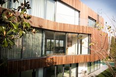 a modern house with wooden balconies and glass walls on the outside, overlooking a garden